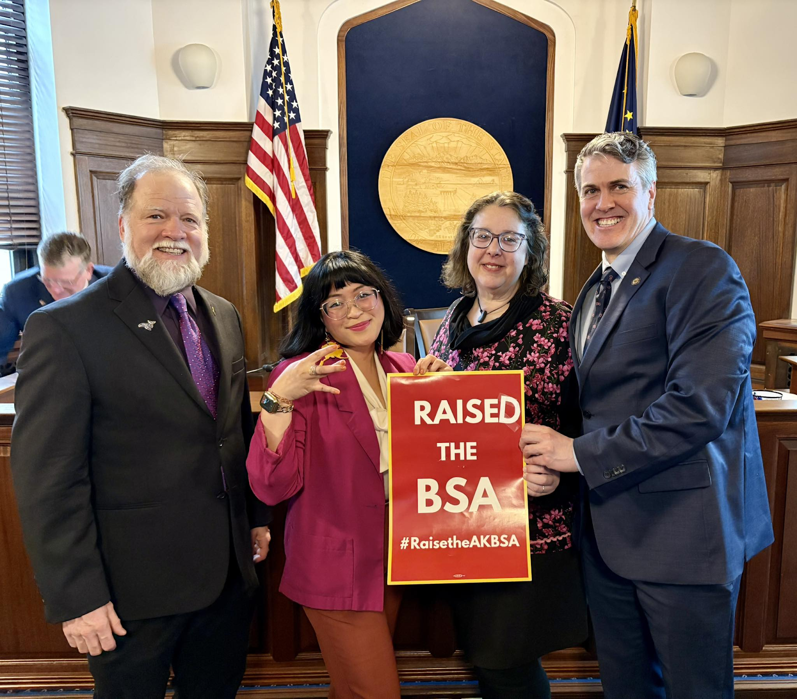 Alaska State Legislators holding a sign that says "Raised the BSA".