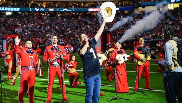 Picture of Bobby singing at a Houston Texans playoff game with mariachi behind him