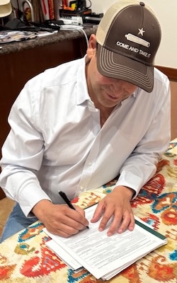 Picture of Bobby signing the paperwork to be on the ballot!