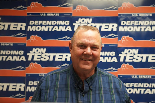 Jon Tester in front of campaign signs