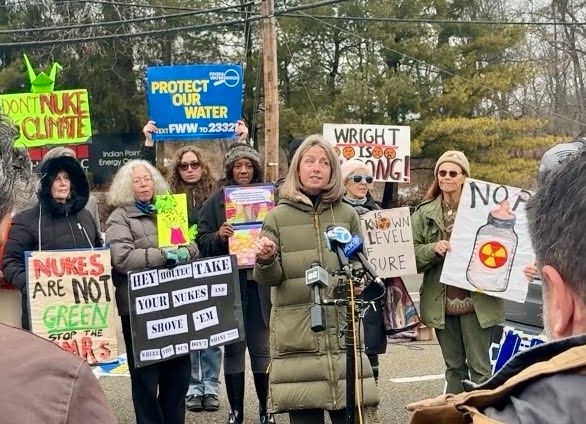 Beth speaking at the protest with supporters around her holding posters