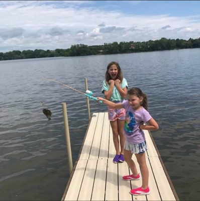 Sisters catch fish together on lake dock