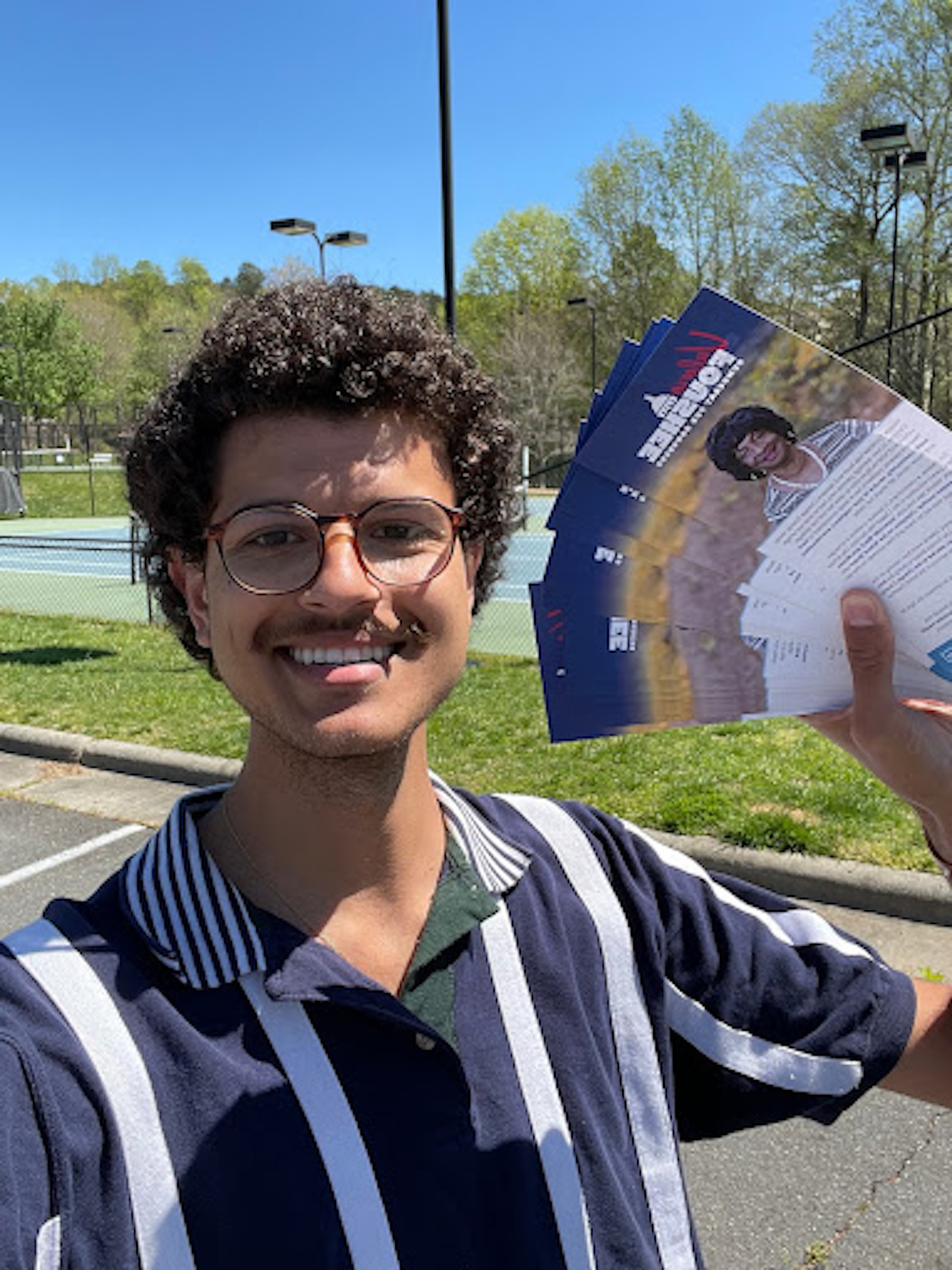 A male canvasser in a striped shirt holding pamphlets